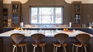 A modern kitchen with a large island, bar stools, and built-in cabinets.