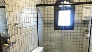 A small bathroom with a toilet, sink, and shower. - Campos Hotel do Sol (Campos do Jordão)