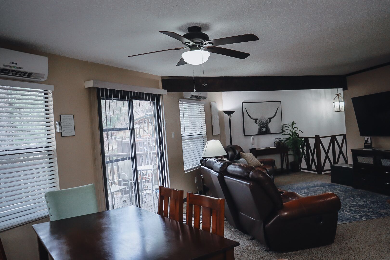 A living room with a ceiling fan, a dining table, and a sofa.
