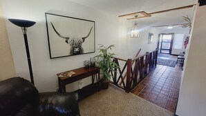 Un pasillo con una obra de arte enmarcada de una cabeza de toro, una planta en maceta, una consola de madera y un sillón de cuero.