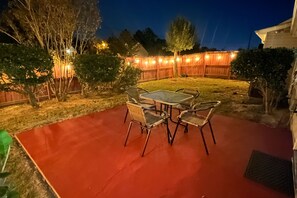 Relax in this serene patio area surrounded by lush greenery, featuring a table and four chairs.