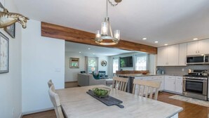 A modern kitchen with white cabinets, stainless steel appliances, and a wooden dining table.