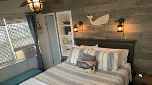 Ein gemütliches Schlafzimmer mit einem Bett, einer Sitzbank und einem an der Wand befestigten Regal mit Dekoration.