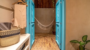 A narrow hallway with blue doors leading to a room. A woven basket is placed on a white shelf, and a potted plant is visible to the right. - BACALARI HOTEL BOUTIQUE (Bacalar)
