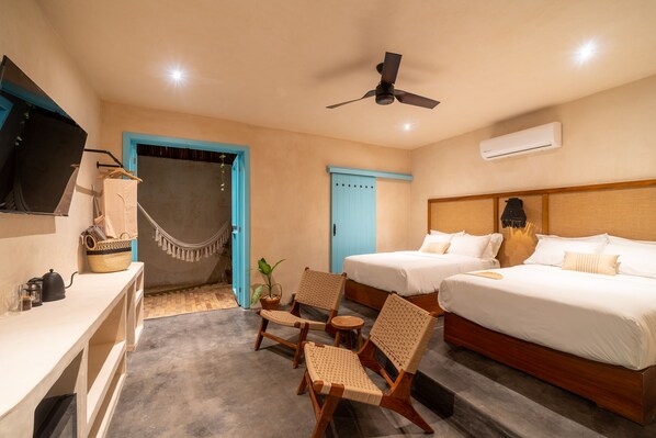 Habitación de hotel con dos camas, un escritorio, una silla, un ventilador de techo y un equipo de aire acondicionado.