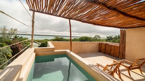 A rooftop pool with a clear view of the ocean, surrounded by lush greenery and bamboo furniture. - BACALARI HOTEL BOUTIQUE (Bacalar)
