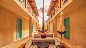 A corridor with a sofa and a bench, wooden railings, and a palm tree. - BACALARI HOTEL BOUTIQUE (Bacalar)