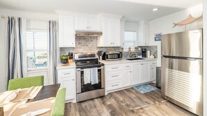 Una cocina moderna con armarios blancos, un refrigerador de acero inoxidable, un microondas y un horno.