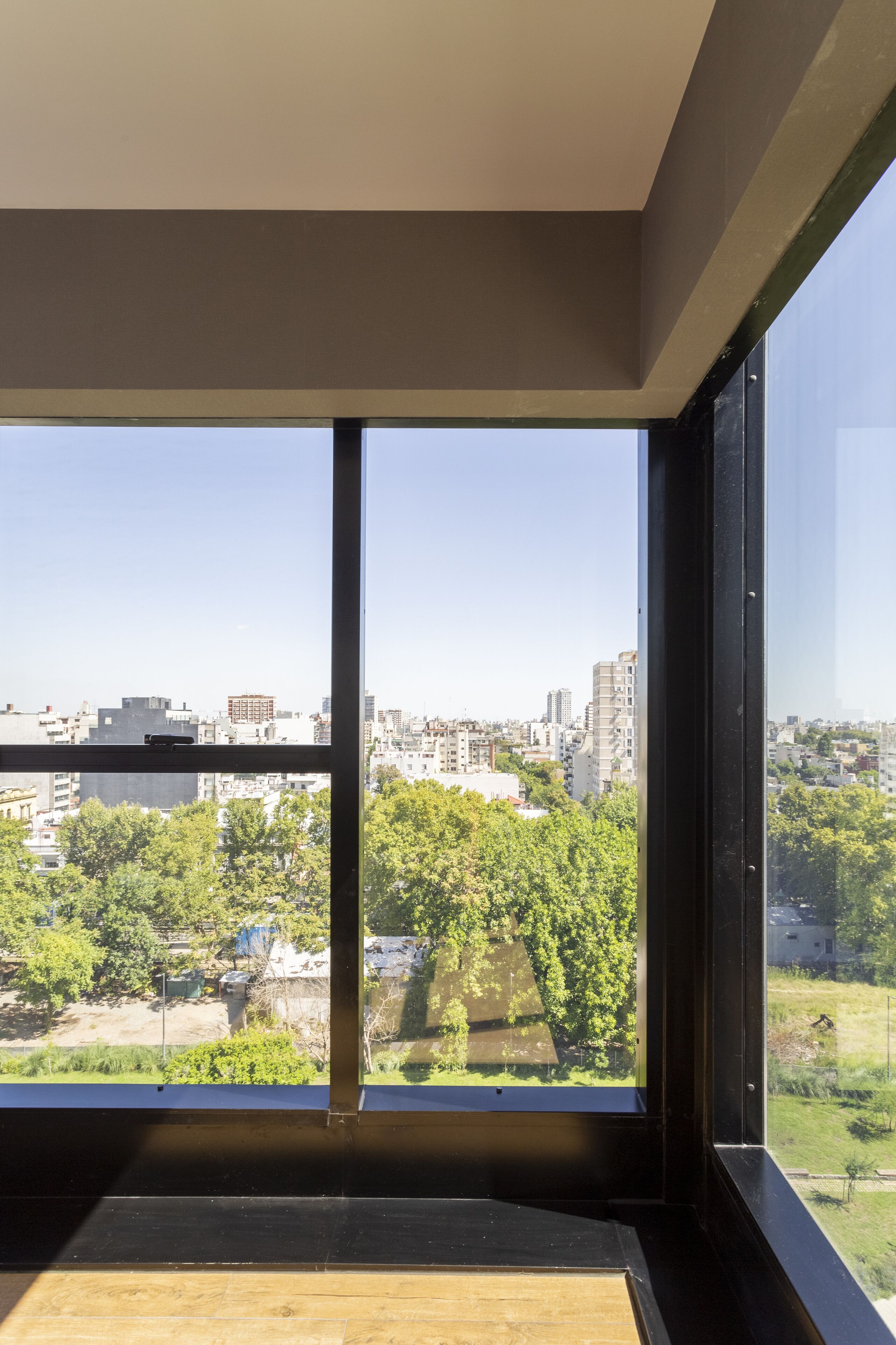 A room with large windows offering a view of a cityscape and greenery.