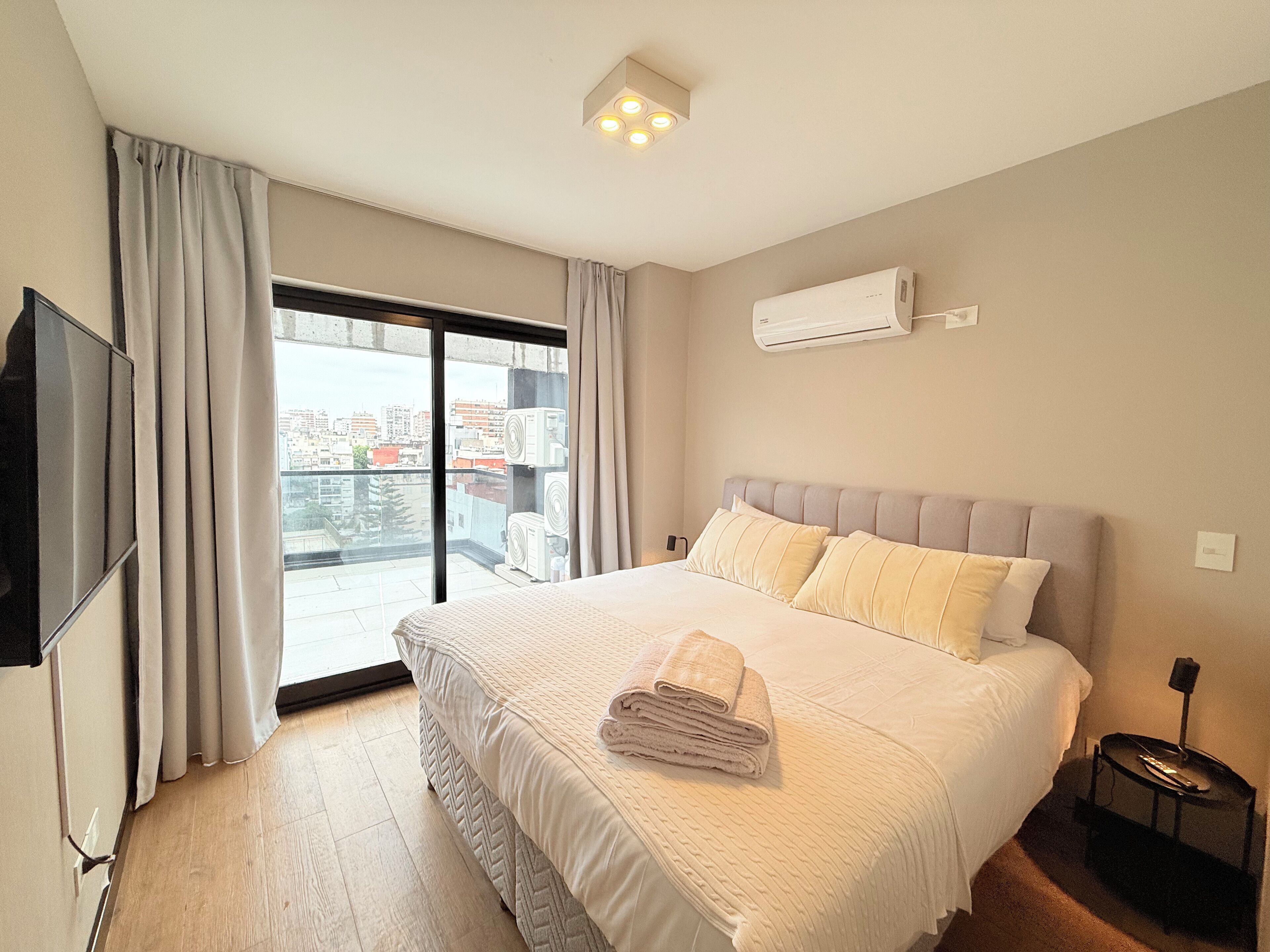 Une chambre d’hôtel dotée d’un grand lit, d’une télévision à écran plat, d’un balcon avec des rideaux et d’un système de climatisation.