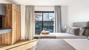 Una habitación de hotel moderna con una cama grande, un armario, un televisor y un balcón con cortinas.