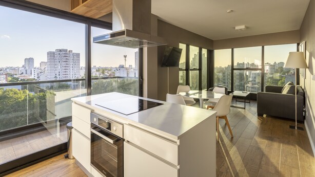 Una cocina moderna con una isla grande, un comedor con mesa y sillas, y un sofá.