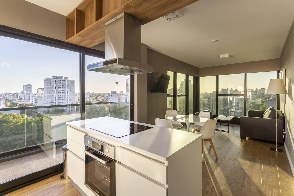 A modern kitchen with a large island, a dining area with a table and chairs, and a sofa.