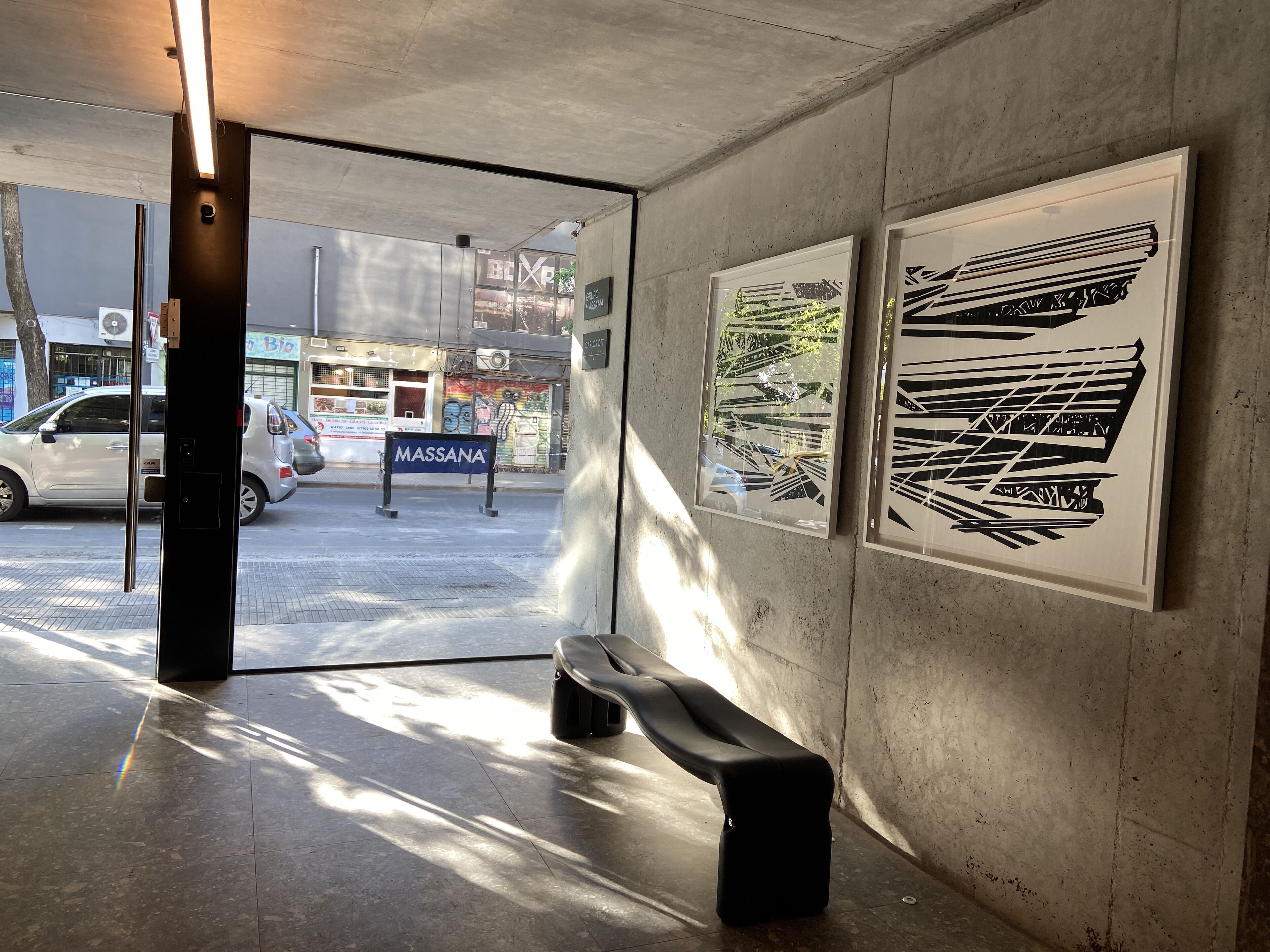 Een binnenruimte met een bank, betonnen muren en kunstwerken.