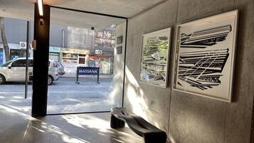 Een binnenruimte met een bank, betonnen muren en kunstwerken.