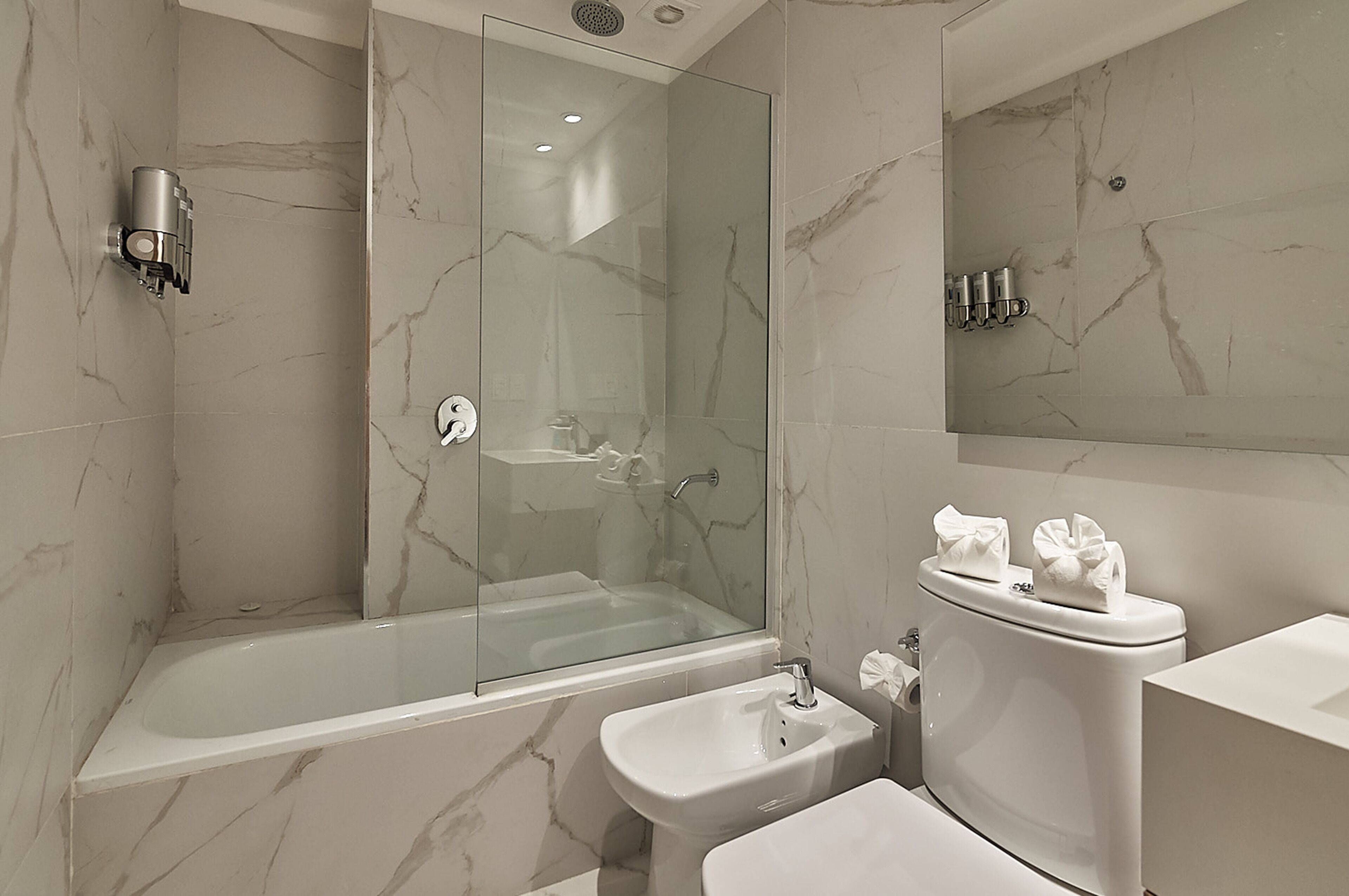 A modern bathroom with a glass-enclosed shower, a standalone sink, and a toilet.