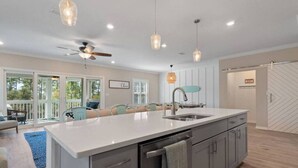 A modern kitchen with a large island, pendant lighting, and a view of the outdoors. - 4BR, free shuttle, gym, pool, BBQ, beach access (Pensacola)