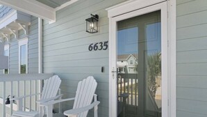 A porch with two white Adirondack chairs, a glass door with a number 6635, and a small lantern above the door. - 4BR, free shuttle, gym, pool, BBQ, beach access (Pensacola)