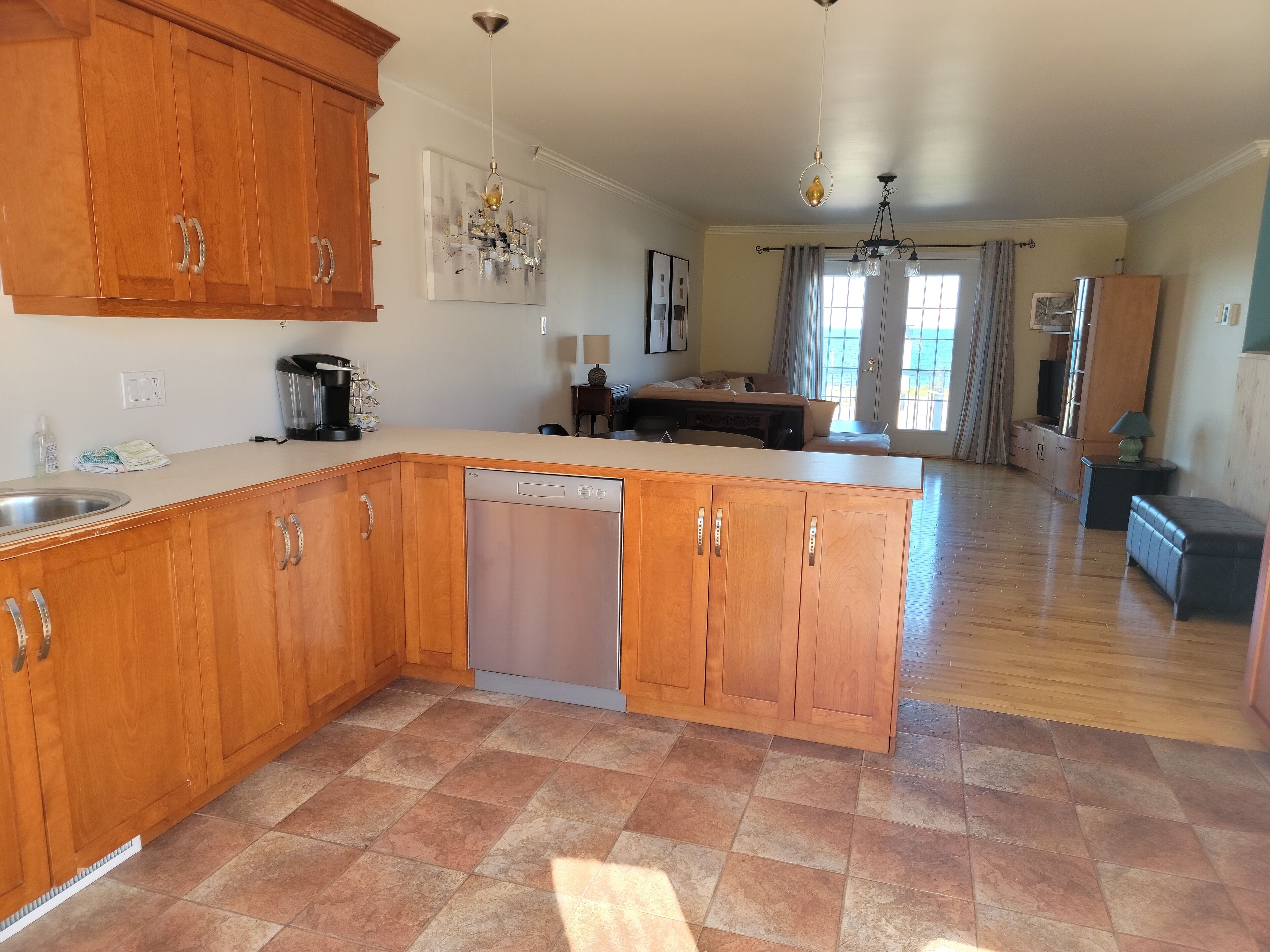 A spacious kitchen with wooden cabinets, a dishwasher, and a dining area with a sofa and table.