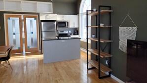Una cocina moderna con una isla central, repisas de madera y un ventanal grande.