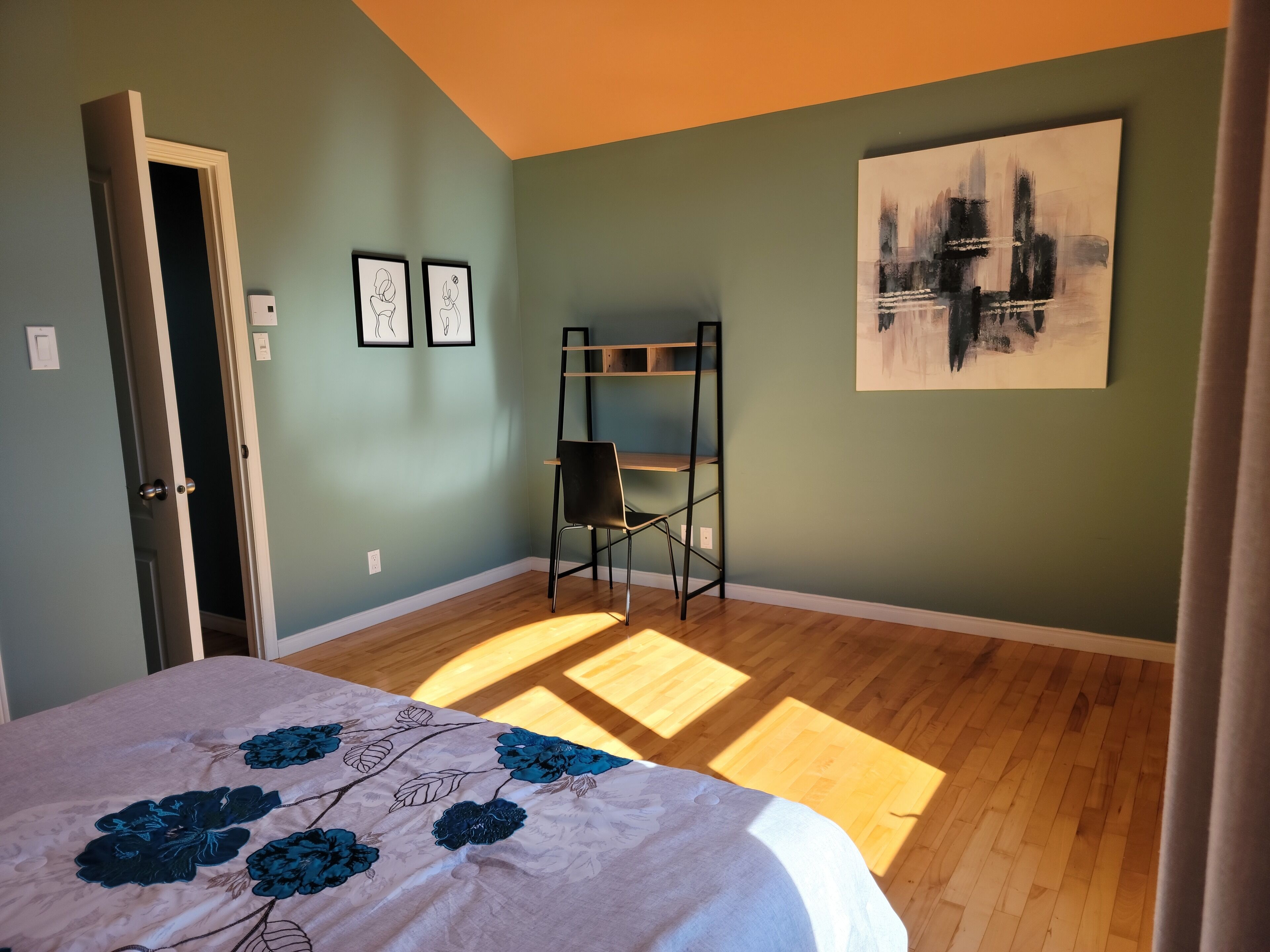 Habitació amb un llit, una cadira, una escala i un quadre a la paret.