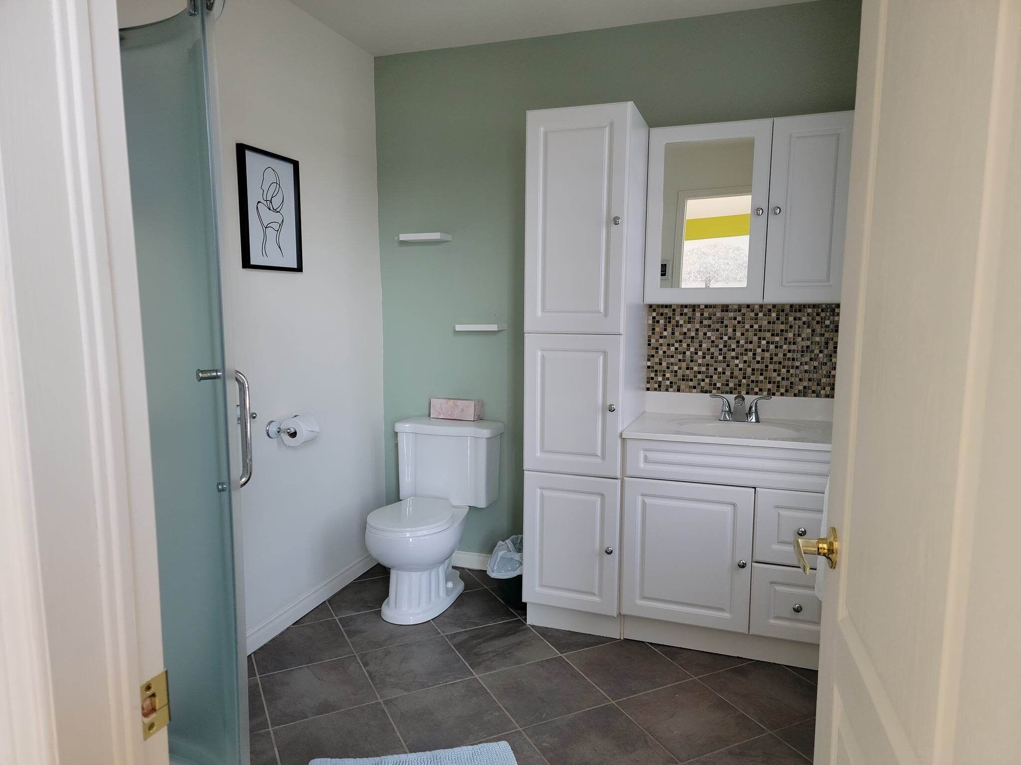 A bathroom with a toilet, a sink, and cabinets.