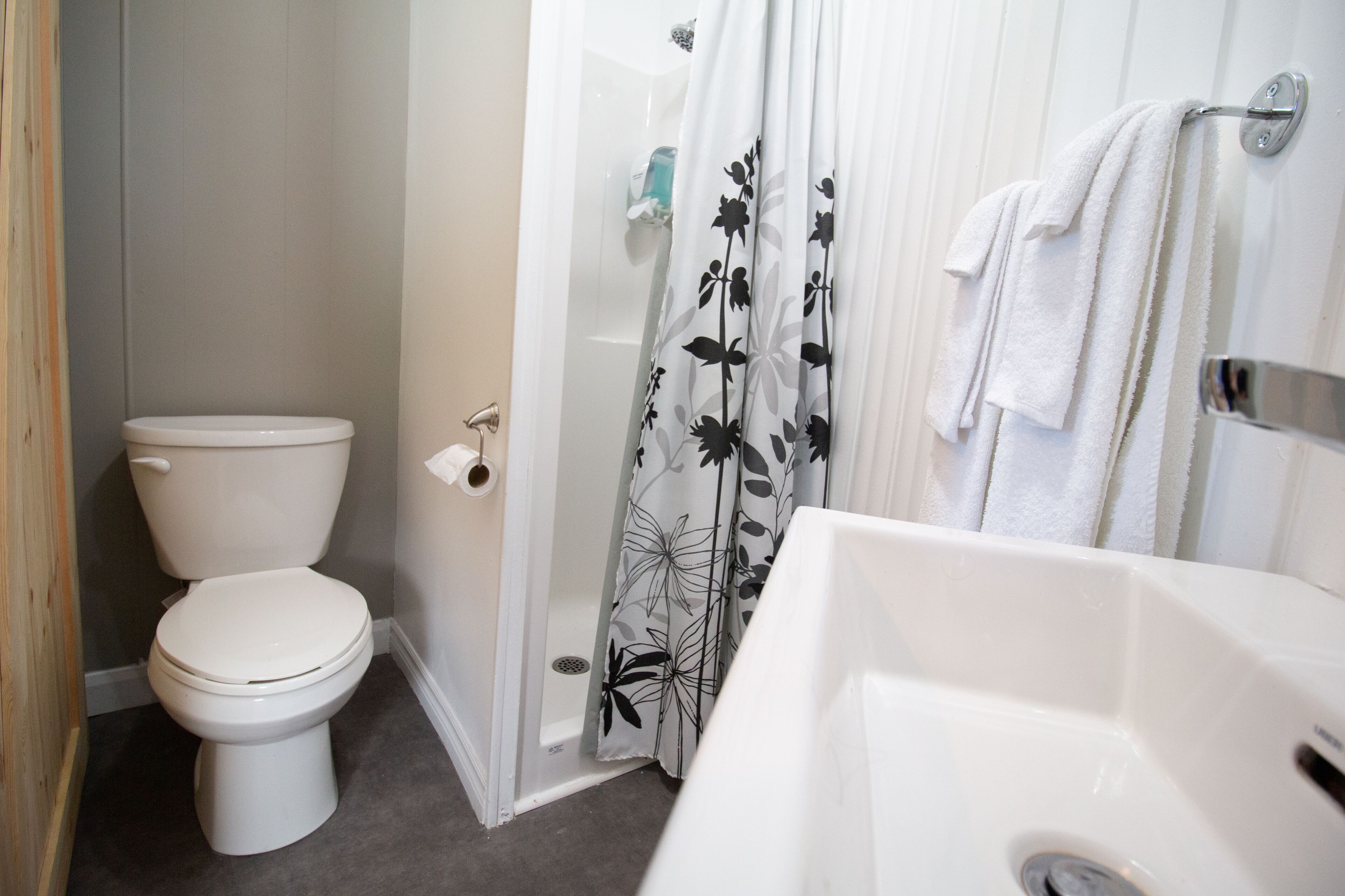 A bathroom with a toilet, shower curtain, and sink.