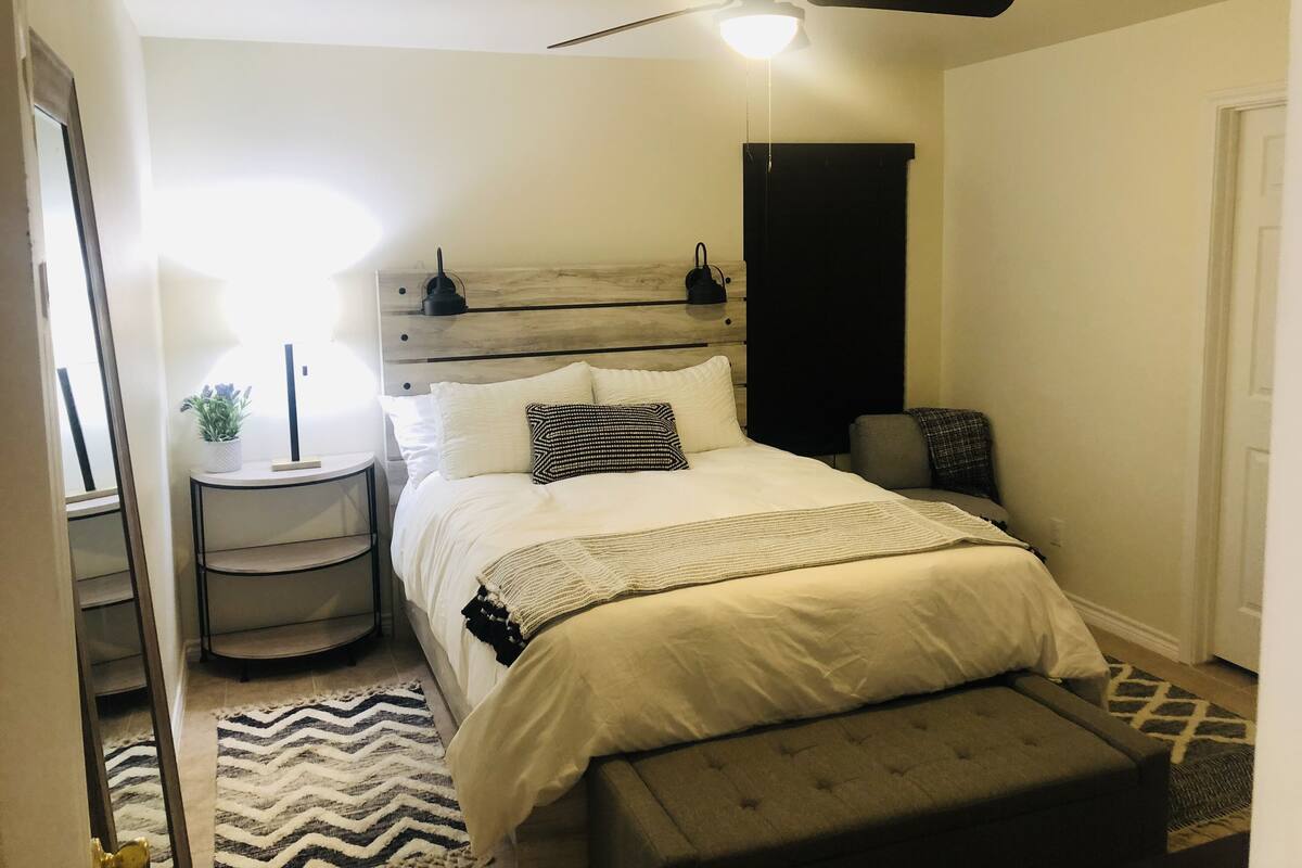 Un dormitorio con cama, mesita de noche, lámpara y ventilador de techo.