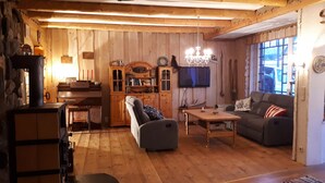 A cozy wooden interior with a fireplace, a sofa, a table, and a television. - Cozy vacation apartment directly on the fjord (Sørbøvågen)
