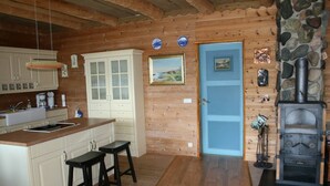 A kitchen with wooden cabinets, a blue door, and a stone fireplace. - Cozy vacation apartment directly on the fjord (Sørbøvågen)
