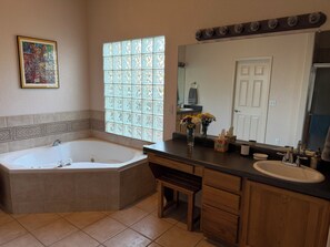 A bathroom with a bathtub, vanity, sink, and a large mirror. - Quiet neighborhood with stunning views of the Organ Mountains. (Las Cruces)