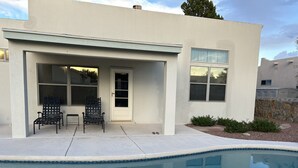 Une maison moderne avec une piscine, deux chaises et une porte.