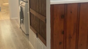 Une buanderie équipée d’un lave-linge, d’un sèche-linge et de lambris en bois sur le mur.