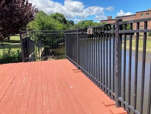 Una terraza de madera con barandilla de metal que da a un cuerpo de agua.