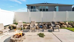 Ein Garten mit Feuerstelle, Liegestühlen und einem weißen Zaun.