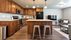 Eine moderne Küche mit Holzschränken, Edelstahlgeräten und einer zentralen Kochinsel mit Hockern.