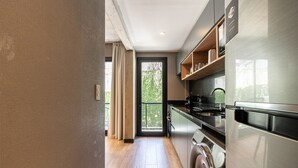 Una cocina moderna con electrodomésticos de acero inoxidable, piso de madera y vistas a través de la puerta.