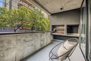 A balcony with a concrete wall, a metal chair, and a grill area. - Live Palermo Hollywood Boutique Apartments (Buenos Aires)