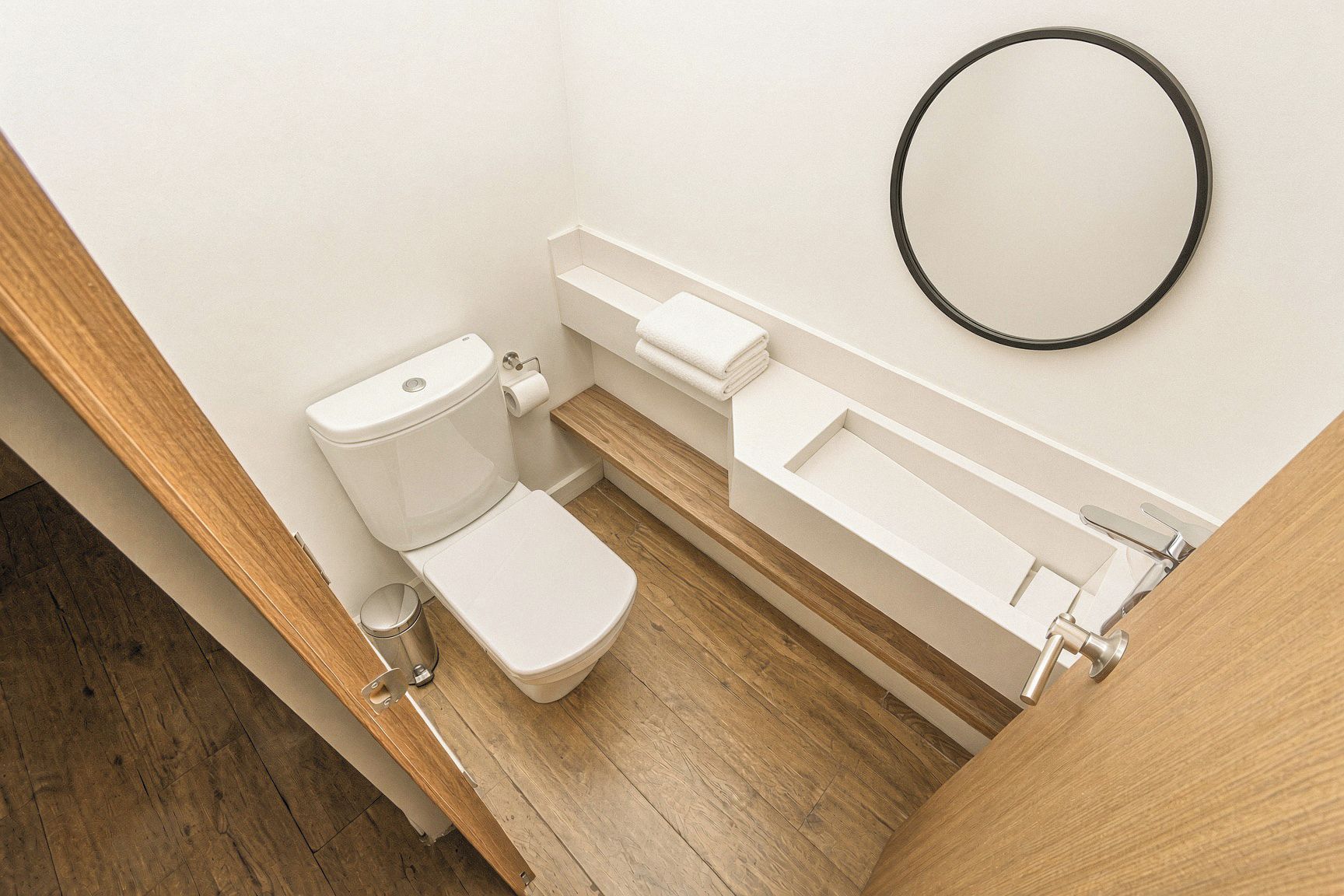 A modern bathroom with a toilet, sink, and mirror.