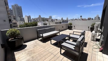 Terraza en la azotea con un conjunto de sofás, una mesita y plantas en macetas.