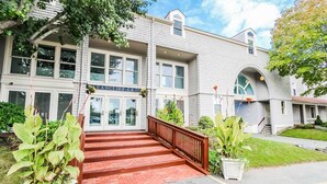A two-story building with a brick facade, a wooden staircase leading to the entrance, and a sign above the doors. - Oceancliff Resort I & II (Newport)