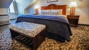 A hotel room with a bed, two bedside tables with lamps, a bench, and a picture on the wall. - Oceancliff Resort I & II (Newport)