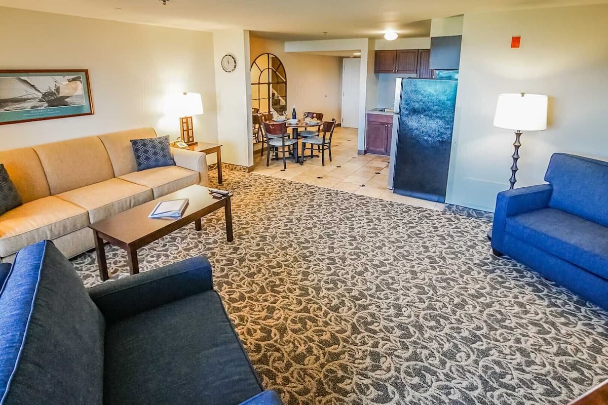 A living room with a sofa, coffee table, patterned rug, and a dining area with chairs and a table.