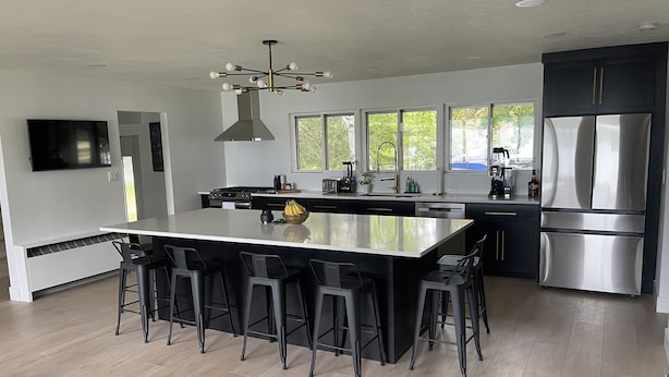 A modern kitchen with a central island, bar stools, stainless steel appliances, and large windows. - Lake Home perfect for families in a quiet Lake Antoine neighborhood.  (Iron Mountain)