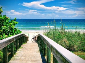A wooden boardwalk leading to a beach with a bicycle parked on it. - Tranquil Beach House with Private Pool - Steps to the Ocean (Ponce Inlet)