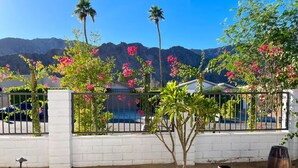 Un jardin agrémenté de plantes en pot, une clôture blanche et une vue sur les montagnes.