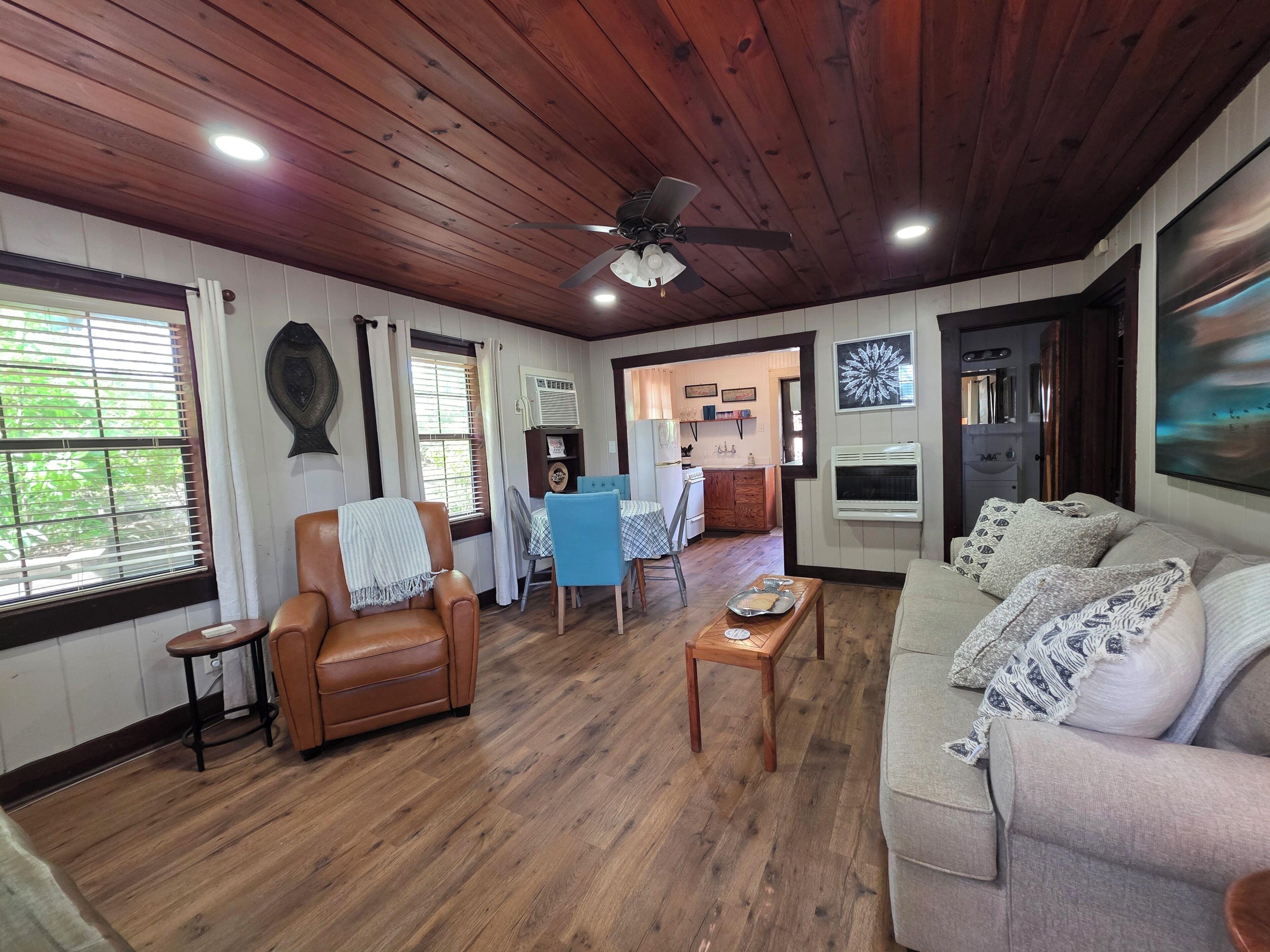 Un salón acogedor con un sillón de cuero marrón, un sofá gris y una mesa de centro de madera.