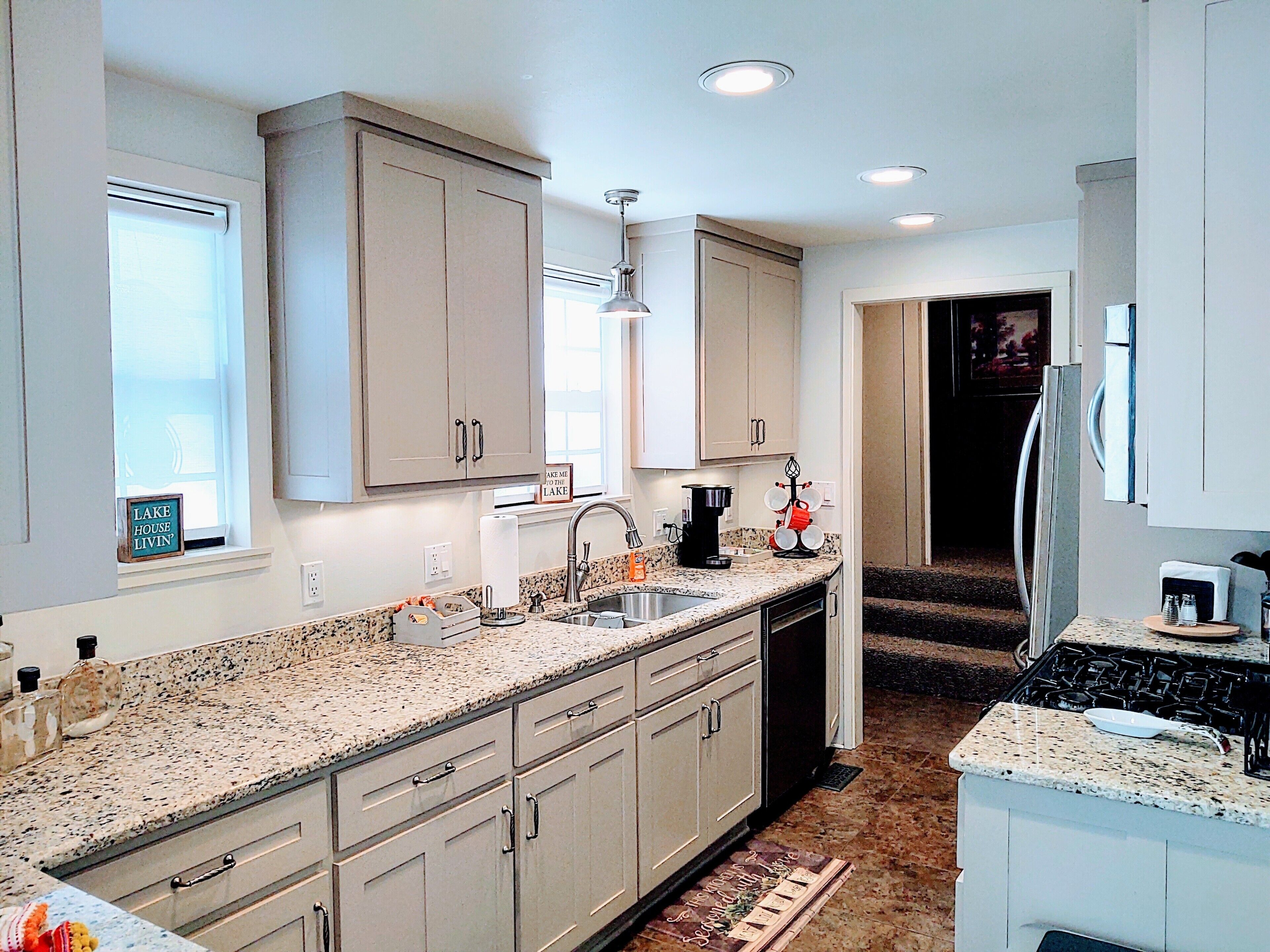 A modern kitchen with granite countertops, stainless steel appliances, and light-colored cabinetry.