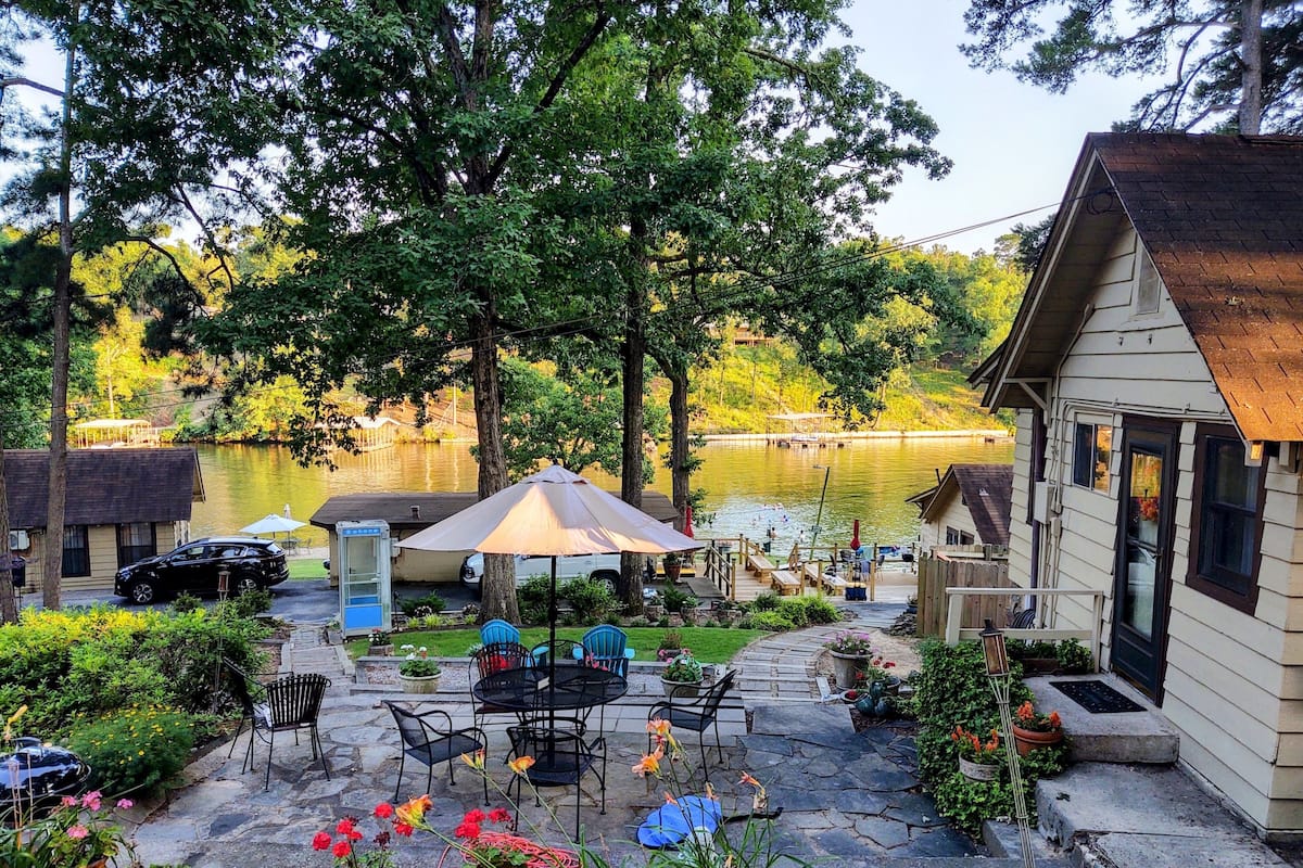 A lakeside patio with outdoor furniture, a covered seating area, and a view of the lake.