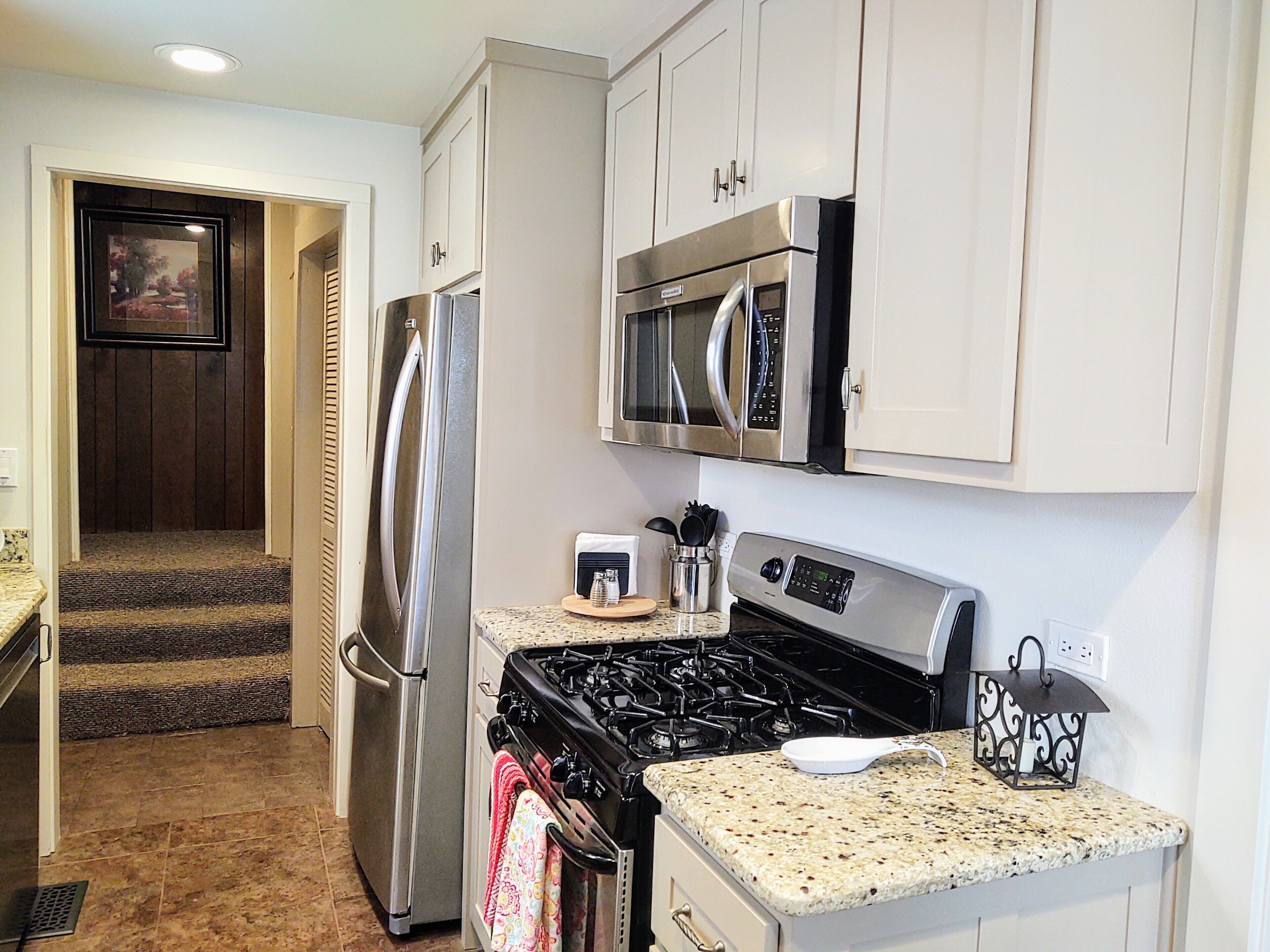 A kitchen with stainless steel appliances, a granite countertop, and white cabinetry.